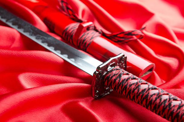 Japanilainen miekka takana punainen satiini tausta
 - Valokuva, kuva