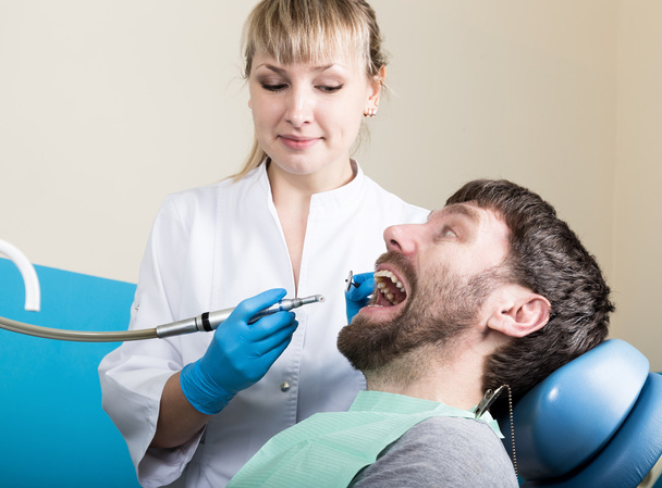 Doctor examines the oral cavity on tooth decay. Caries protection. Tooth decay treatment. Dentist working with dental polymerization lamp in oral cavity - Valokuva, kuva