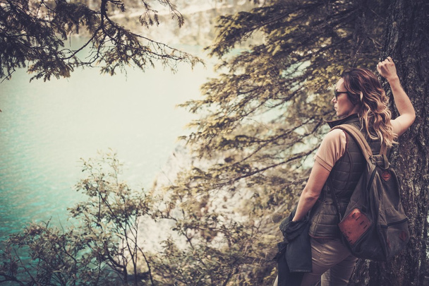 Mujer excursionista con mochila disfrutando de increíbles paisajes del lago de montaña
. - Foto, imagen