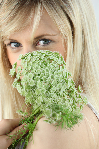 Closeup of a blonde woman holding a green flower in front of her face - Φωτογραφία, εικόνα