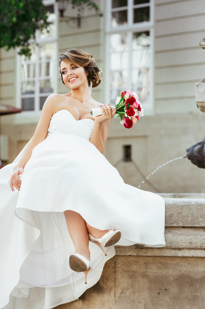Szép menyasszony ült emlékműve közelében  - Fotó, kép
