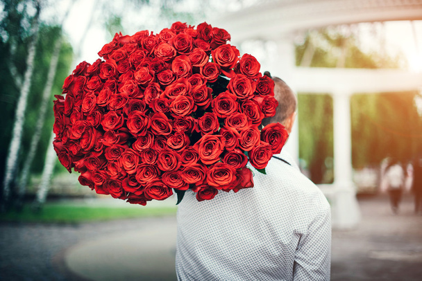 Man with big bouquet of roses   - Фото, изображение