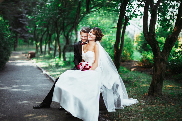 Menyasszony és a vőlegény ül a padon - Fotó, kép