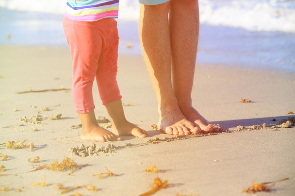father and little daughter feet on beach - 写真・画像