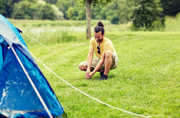 happy man setting up tent outdoors - Фото, изображение