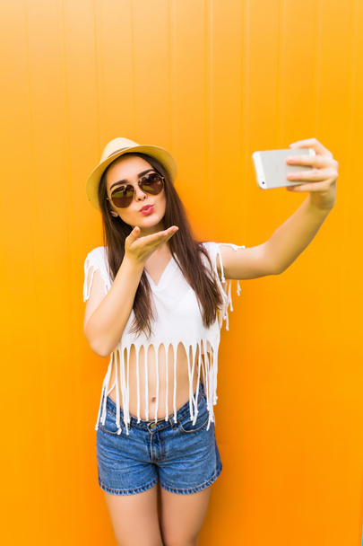 woman makes self portrait on smartphone  over city color wall background - Valokuva, kuva