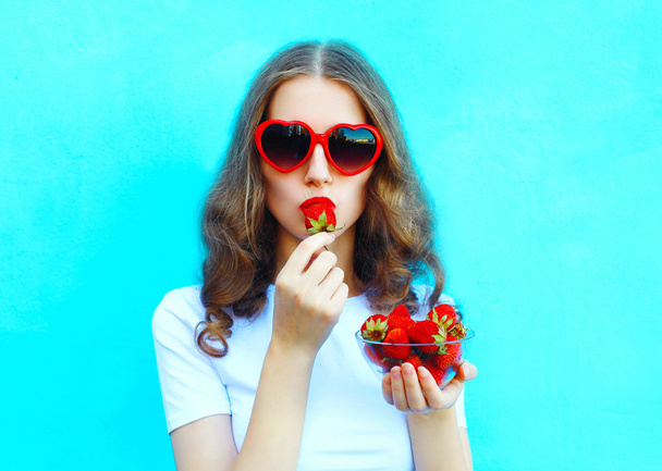Portrait pretty woman with many strawberry over colorful blue ba - Foto, Imagem
