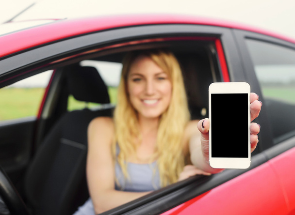 Driver woman showing her smartphone. - Фото, изображение