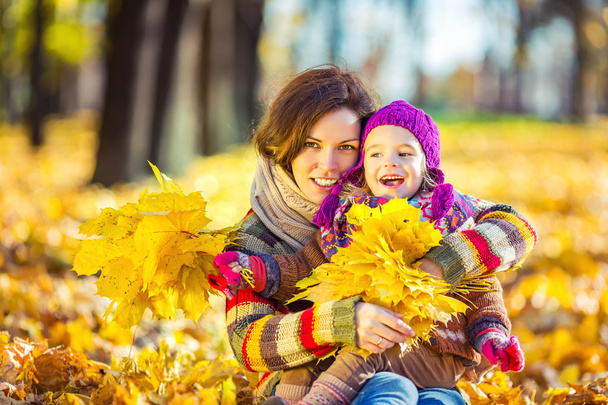 Mother and daughter in playing in autumn park - Фото, изображение