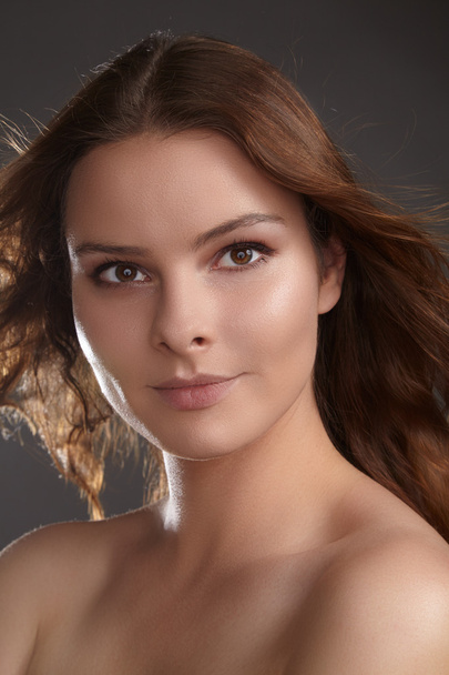 Beautiful young woman model with flying brown color hair. Beauty portrait with clean skin, glow glamour fashion makeup. Make up, curly hairstyle. Hair-care, make-up. Horizontal beauty portrait - Valokuva, kuva