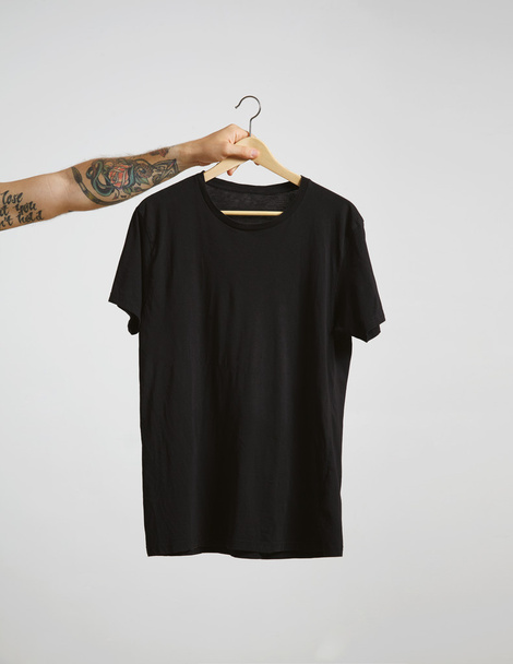 hand holds hang with black t-shirt - Zdjęcie, obraz