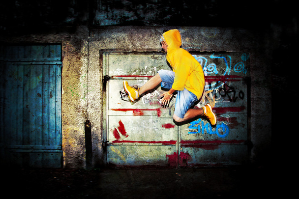 Young man jumping on grunge wall - Photo, Image
