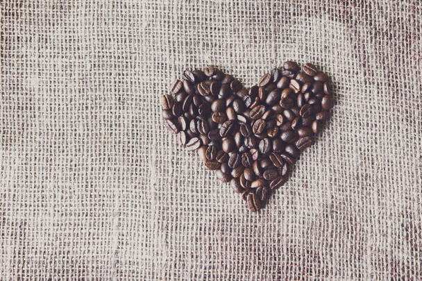 Burlap texture with coffee beans heart shape - Foto, afbeelding