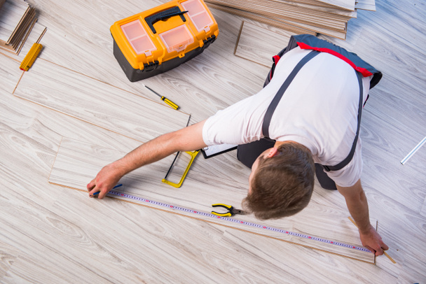 Man laying laminate flooring in construction concept - Valokuva, kuva