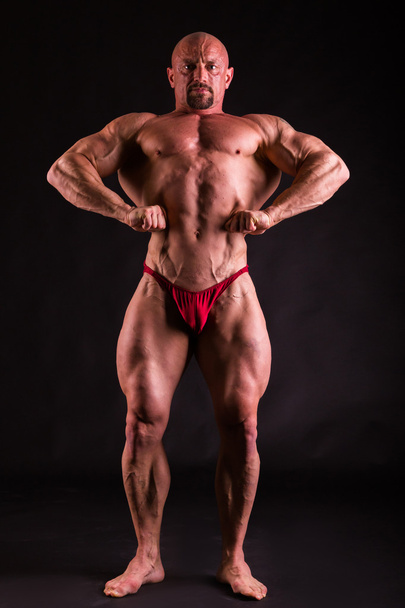 Bodybuilder in demonstrative poses on black - Photo, Image