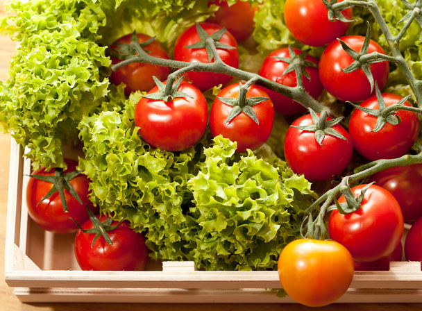 Tomaatit ja salaatti puinen kori pöydällä
 - Valokuva, kuva