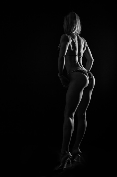 Elegant training, muscular woman on a black background - Фото, изображение