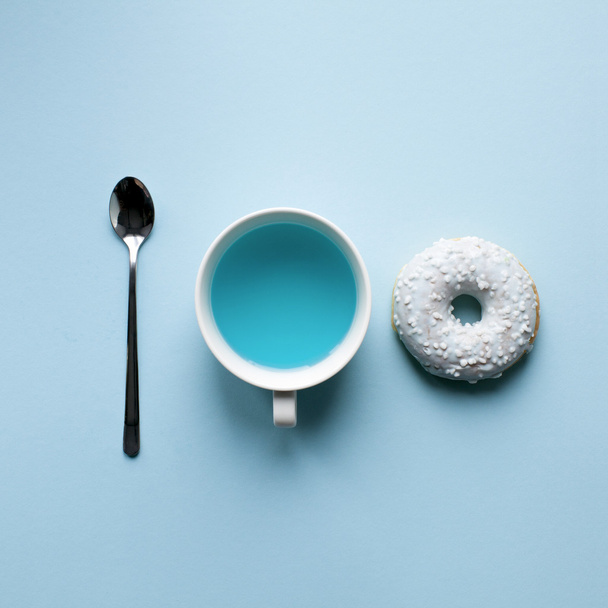 ドーナツ、スプーン、青い水。ミニマリズム アート - 写真・画像