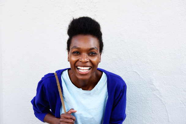 Jeune femme africaine souriant contre un mur blanc
   - Photo, image