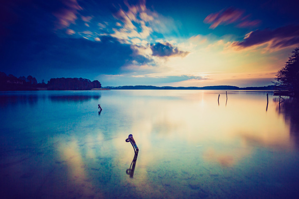 穏やかな湖に沈む夕日のビンテージ写真 - 写真・画像