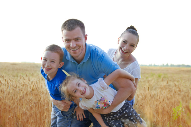Family with two kids having fun among wheat field - Photo, Image