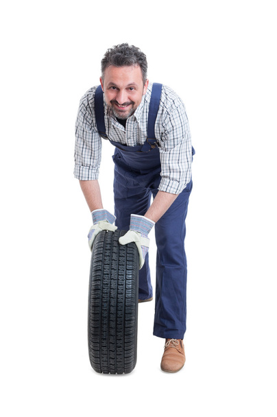 Handsome mechanic in workshop changing car wheel  - Zdjęcie, obraz