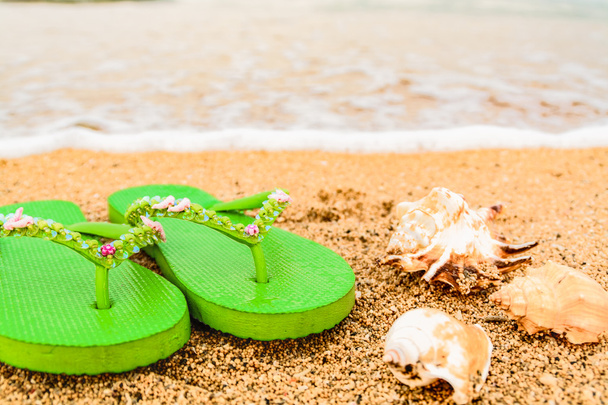 Womens sandals at the beach on the shoreline. - Foto, immagini