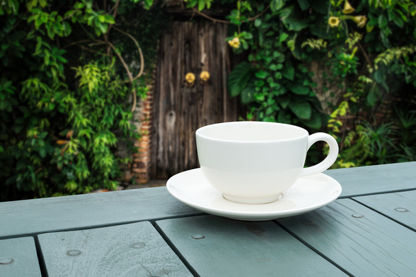 Чашка белого кофе на столе в зеленом парке
. - Фото, изображение