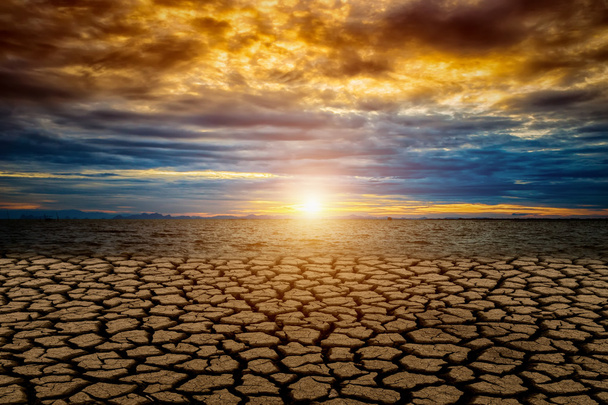 Terreno agrietado del calentamiento global con puesta de sol y nube de color
. - Foto, Imagen