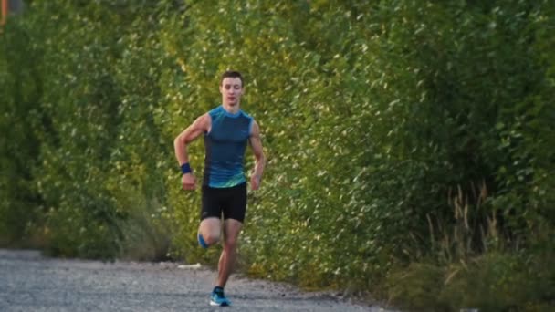 Sterke spier runner man loopt in park bij schemering, vertraagd, brede hoek - Video