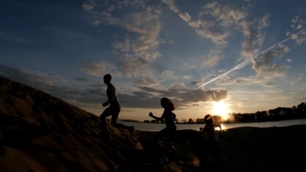 Skupina sportovců - dvě holky a kluk prchají hory, nedaleko řeky v soumraku, zpomalené, silueta - Záběry, video