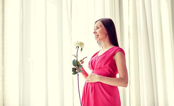 happy pregnant woman with rose flower at home - Φωτογραφία, εικόνα
