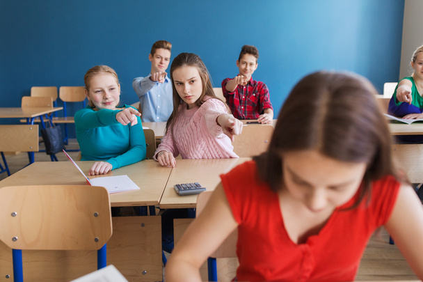 students gossiping behind classmate back at school - Foto, Bild