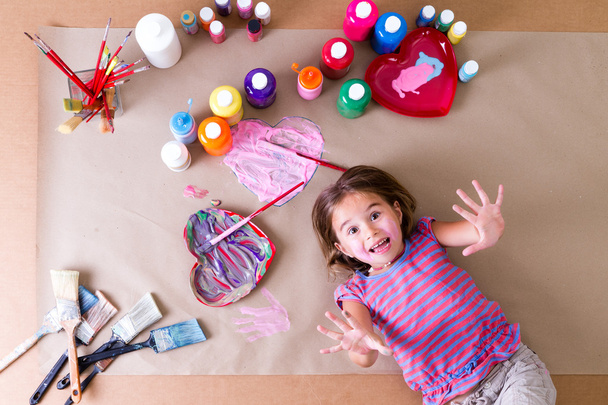 Παιχνιδιάρικο κοριτσάκι που περιβάλλεται από τα χρώματα - Φωτογραφία, εικόνα