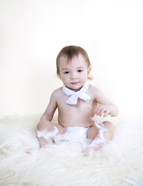 Beautiful sweet baby sitting on floor on white fur, on white bac - Photo, Image