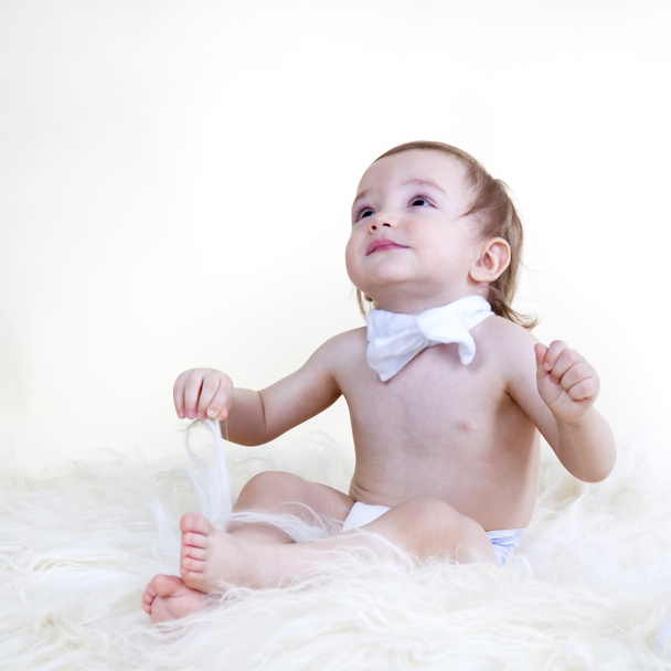 Beyaz bac üzerinde beyaz kürk katta oturan güzel tatlı bebek - Fotoğraf, Görsel