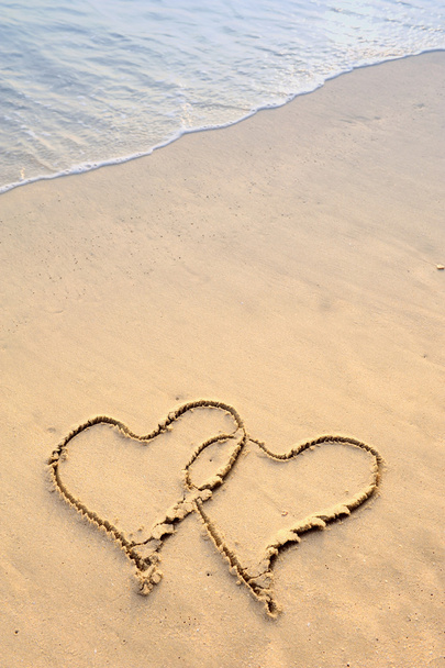 Two hearts drawn on the sand of a beach - 写真・画像