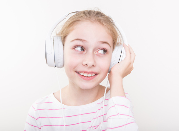 Happy smiling child girl listening music in white headphones. - Foto, imagen