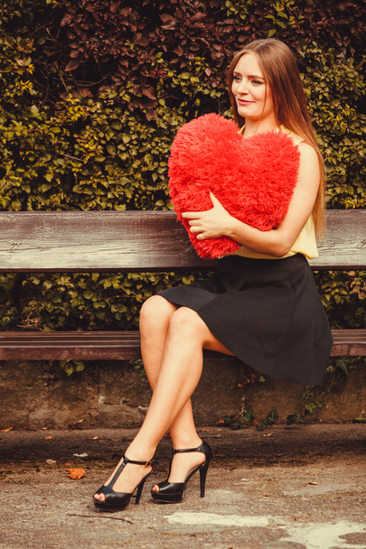 Girl on bench holding heart.  - 写真・画像