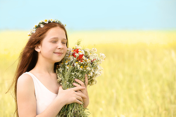 Portrait of girl in meadow with wild spring flowers bouquet - 写真・画像
