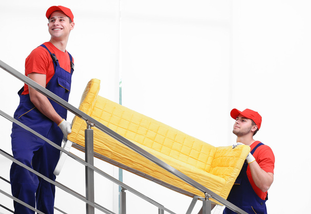 Dos trabajadores varones con sofá amarillo en las escaleras
 - Foto, Imagen