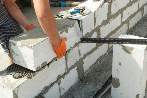 Mason zarovnává provzdušněný autoklávovaný betonový blok zbudované zdi domu - Fotografie, Obrázek