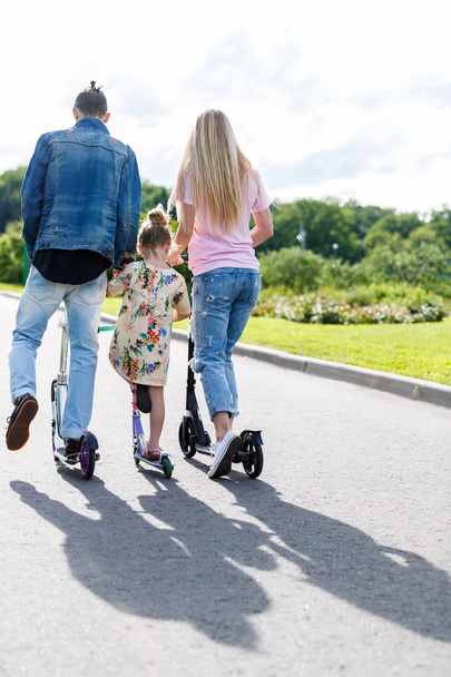 Família com scooters no parque
 - Foto, Imagem