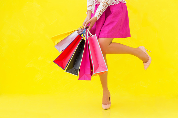 Woman with sexy legs holding shopping bags - Fotó, kép
