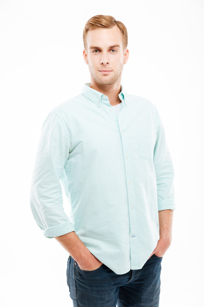Serious attractive young man standing with hands in pockets - Photo, image