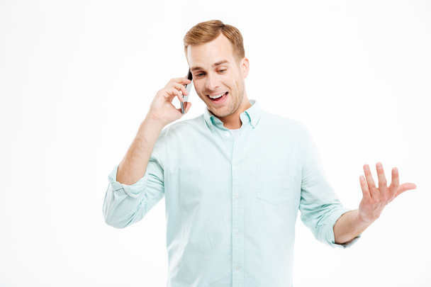 Cheerful attractive young businessman standing and talking on cell phone - Foto, Imagen
