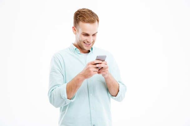 Happy attractive young businessman using smartphone and smiling - 写真・画像
