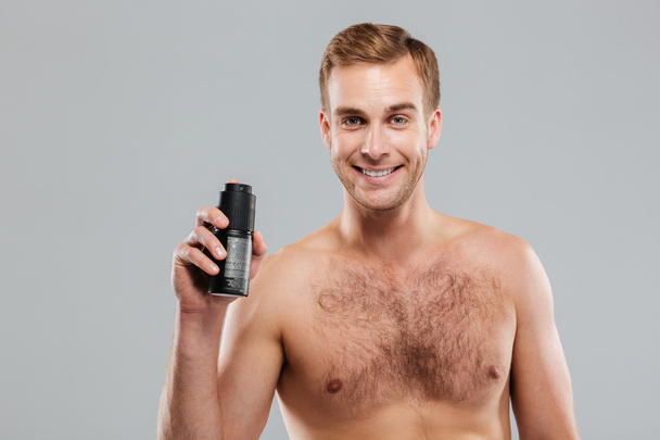 Smiling handsome man holding deodorant - Foto, immagini
