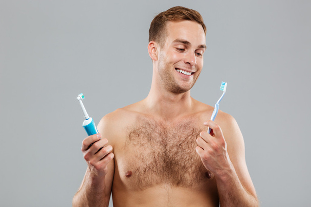 Man choosing toothbrush over gray background - Fotó, kép