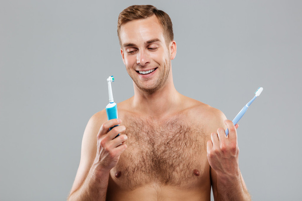 Homme choisissant brosse à dents sur fond gris
 - Photo, image